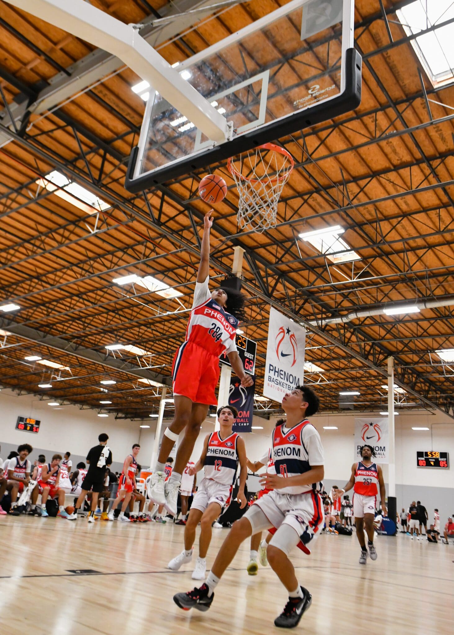 A basketball player attempts a layup during a game in a gymnasium.