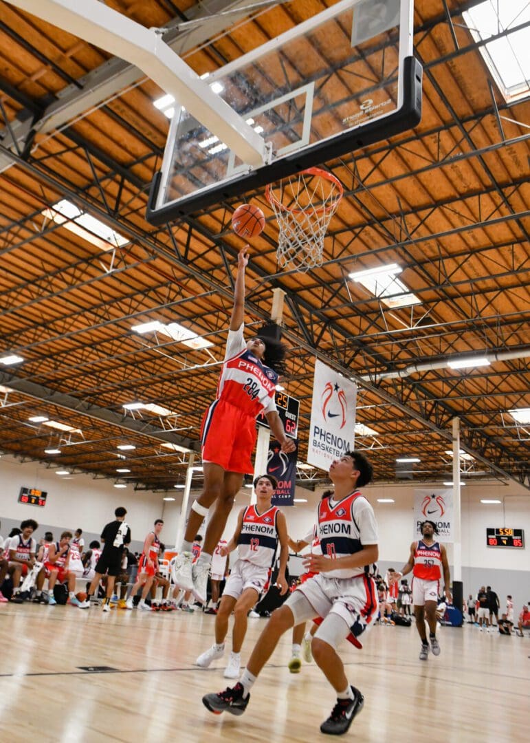 A basketball player attempts a layup during a game in a gymnasium.