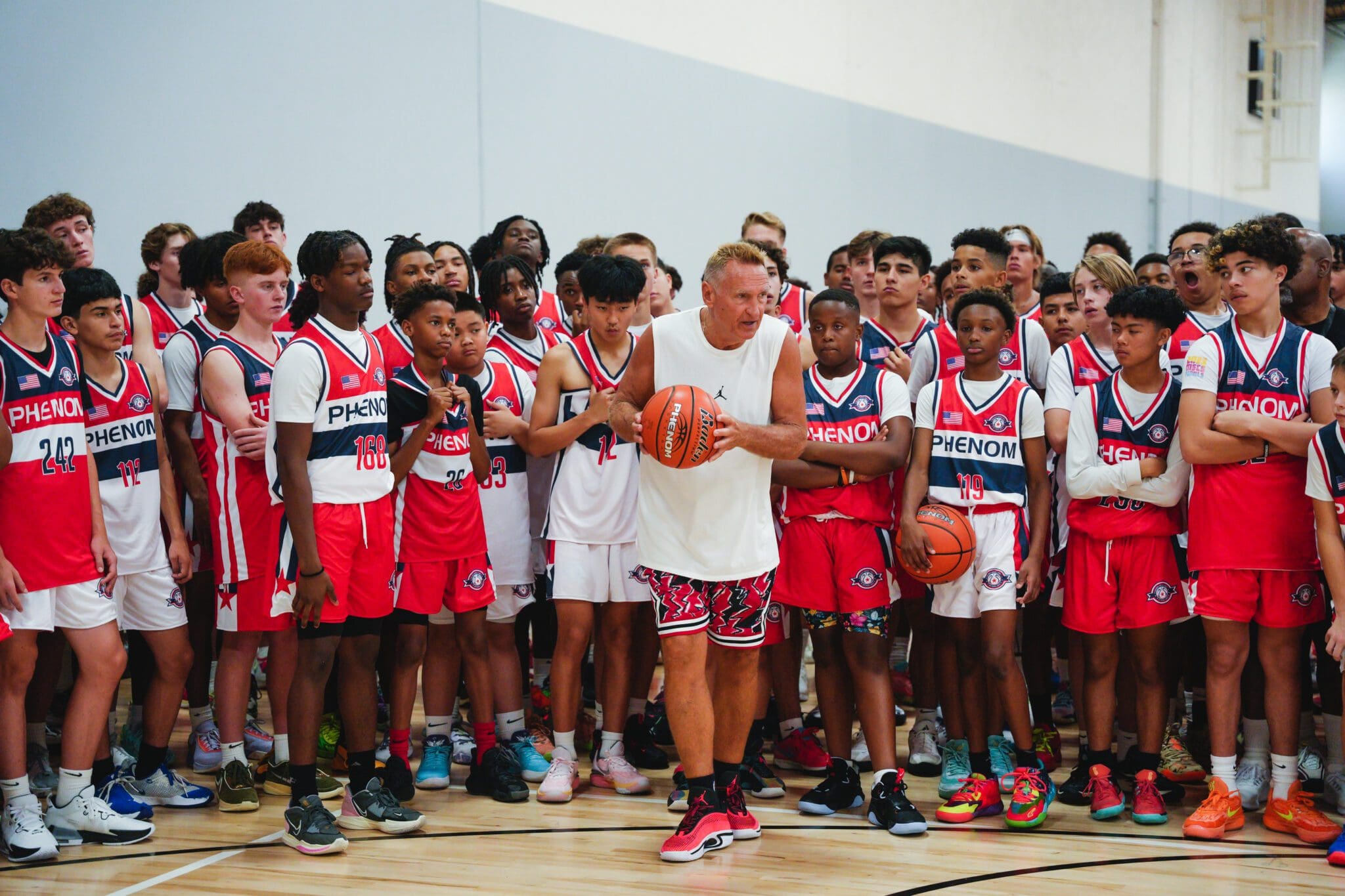 Young basketball players gather around a coach on the court.