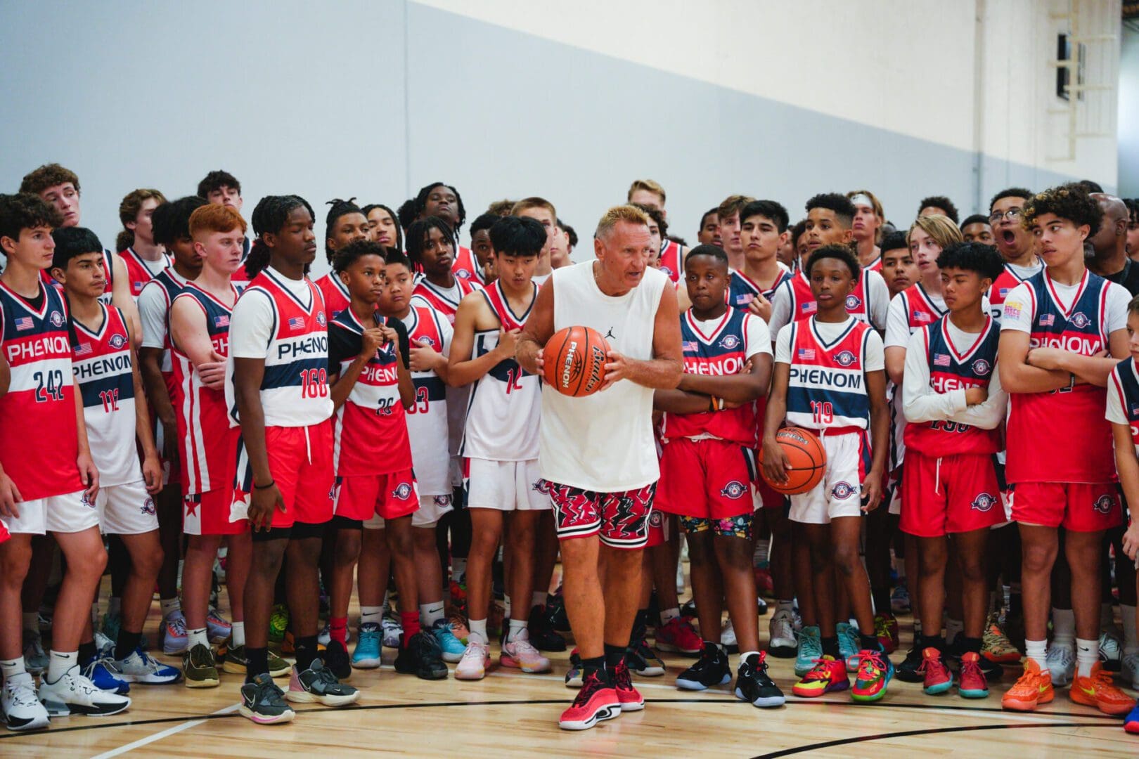 Young basketball players gather around a coach on the court.