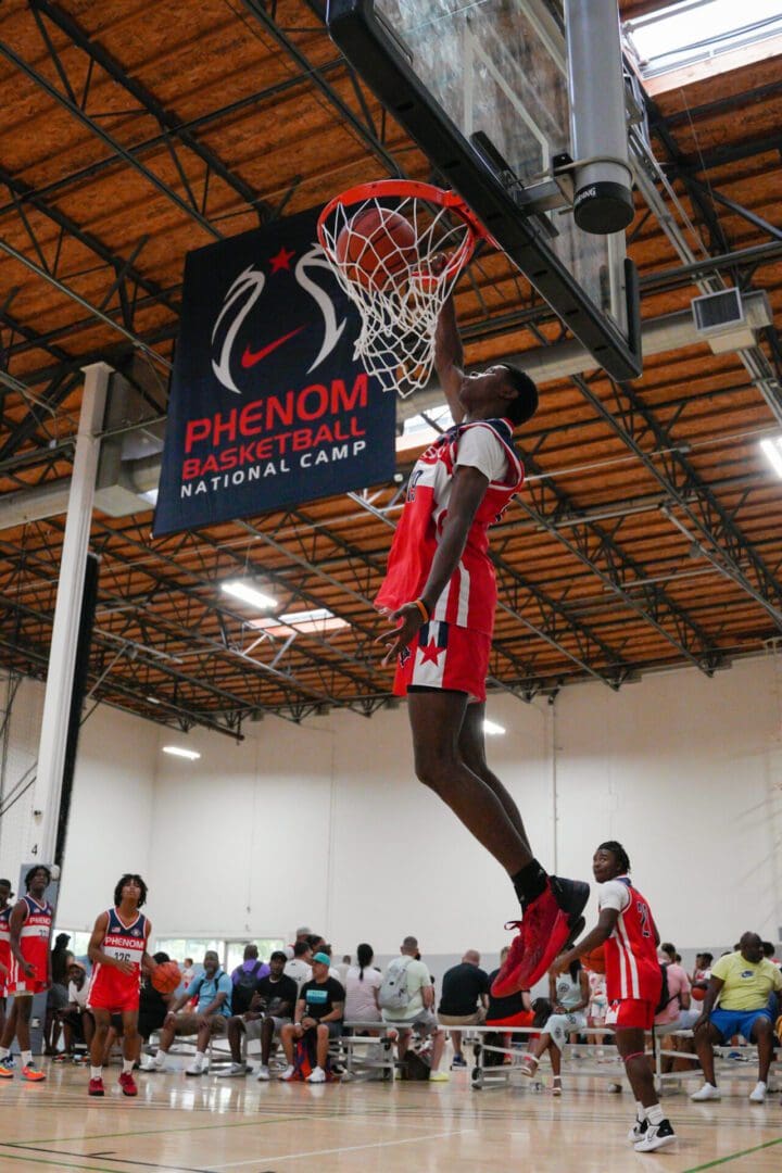 Basketball player mid-air dunking in an indoor gym during a game.