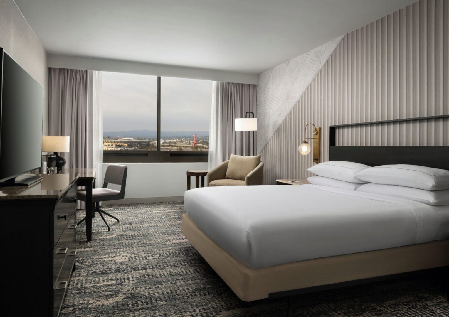 Modern hotel room with large window and cozy seating area.
