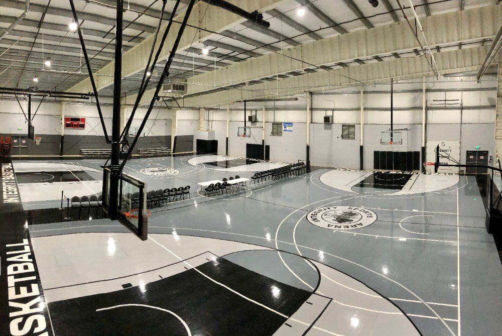 Modern indoor basketball court with sleek black and gray design.